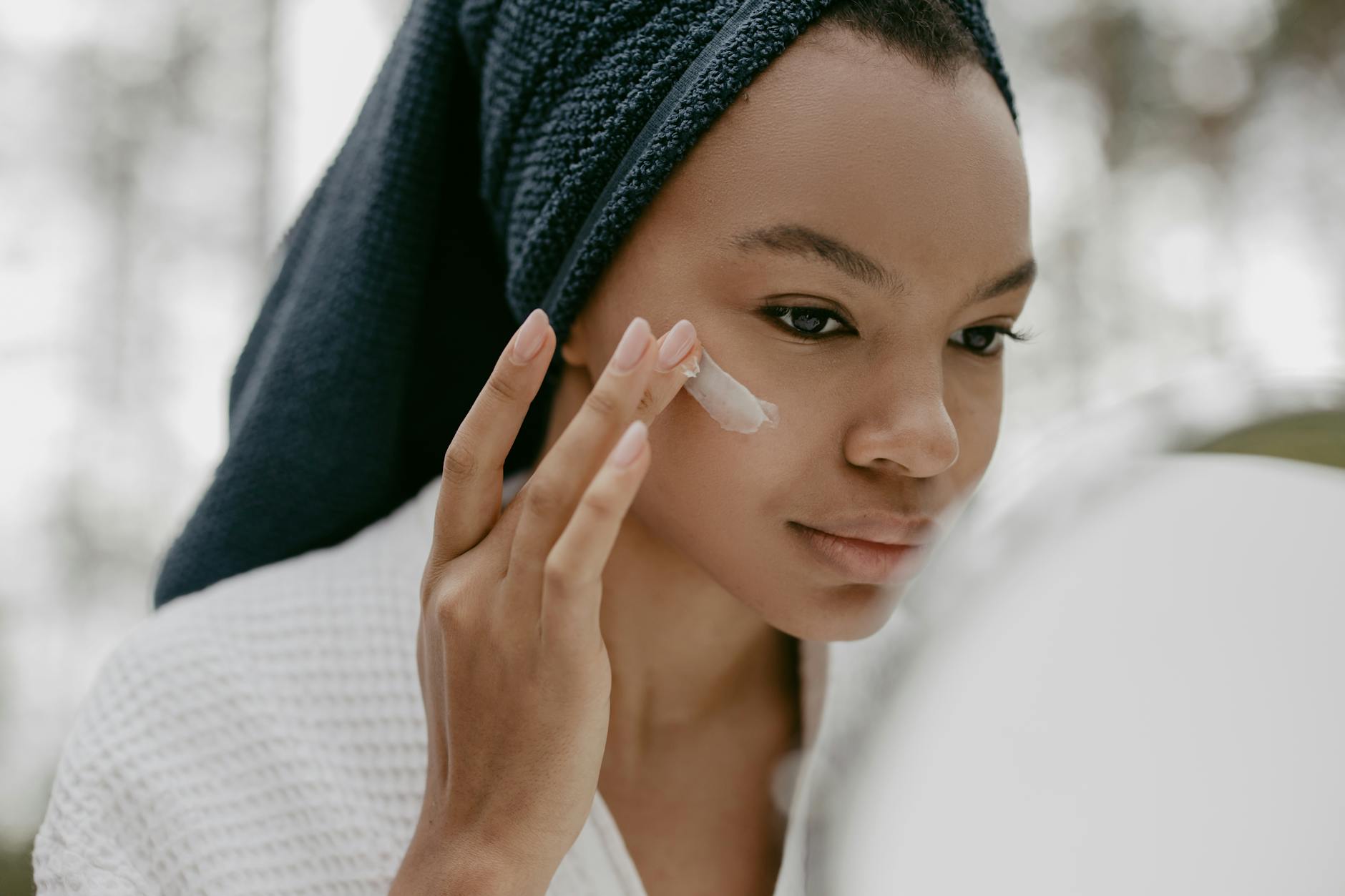 Woman gently applying facial cream as part of a skincare routine, focusing on healthy skin