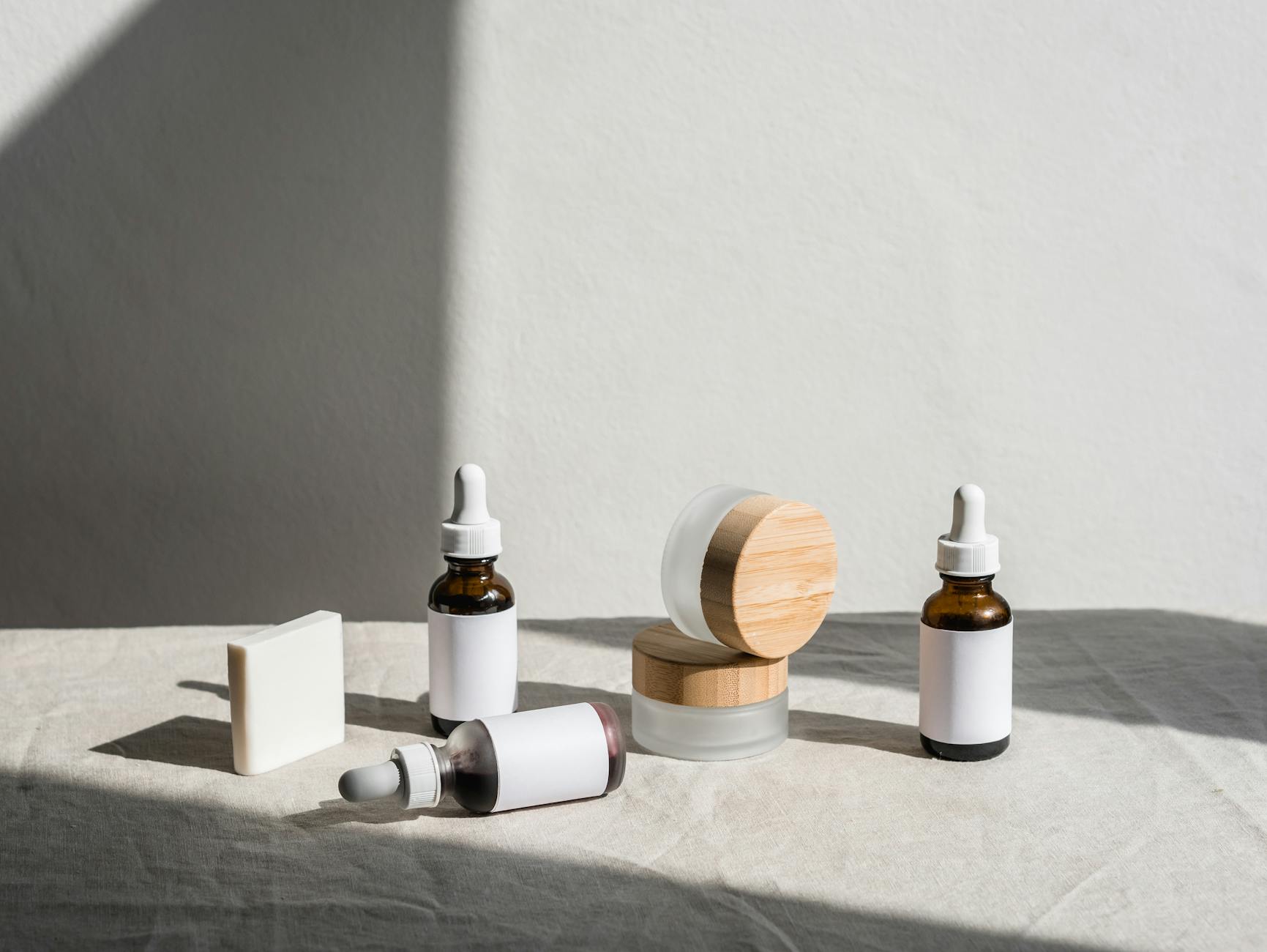Flat lay of skincare products in jars and dropper bottles under soft natural light