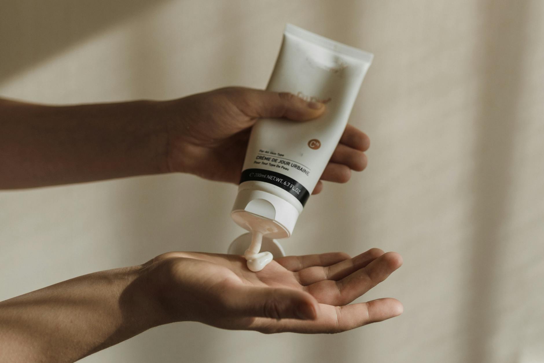 Close-up of a woman squeezing lotion onto her hand, emphasizing skincare and self-care routine