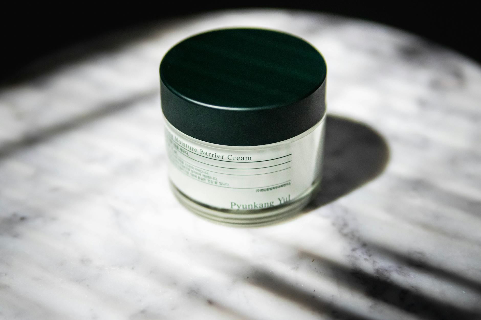 Close-up of a moisture barrier cream jar with stylish packaging on marble
