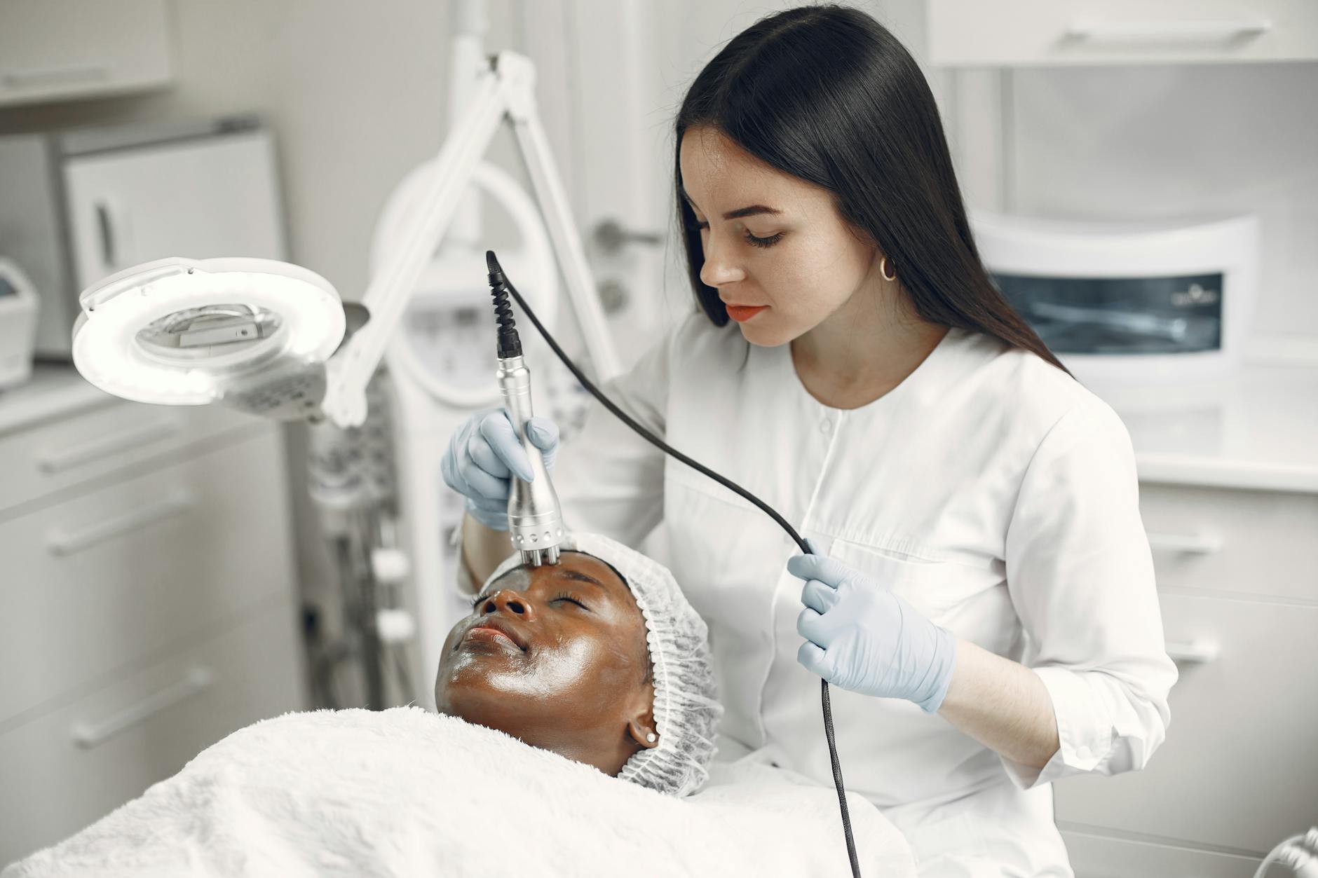 A dermatologist performing a skin tightening treatment on a client in a modern aesthetic clinic