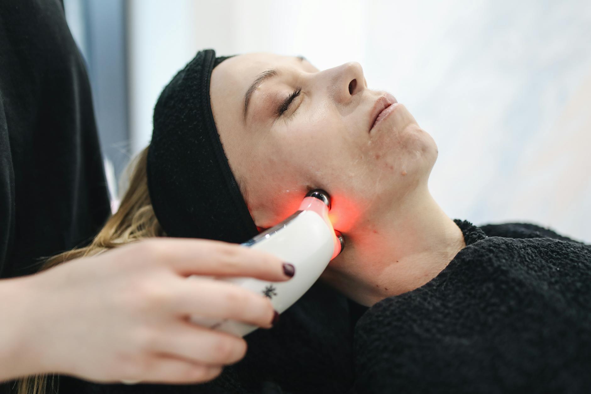 A woman receiving a light-based facial treatment in a modern skincare clinic