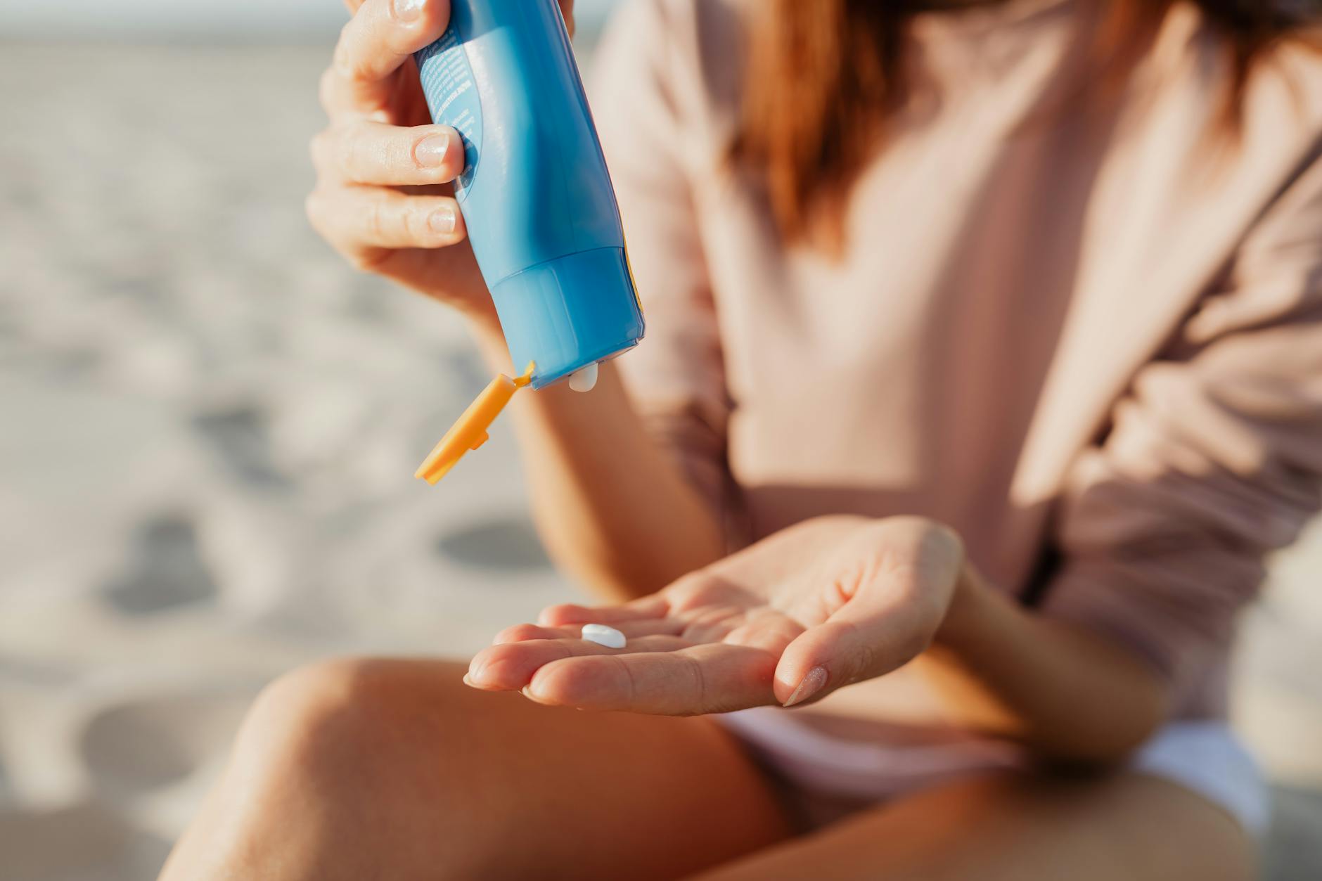 A person applying sunscreen on a sunny day, representing seasonal sun protection in Australia