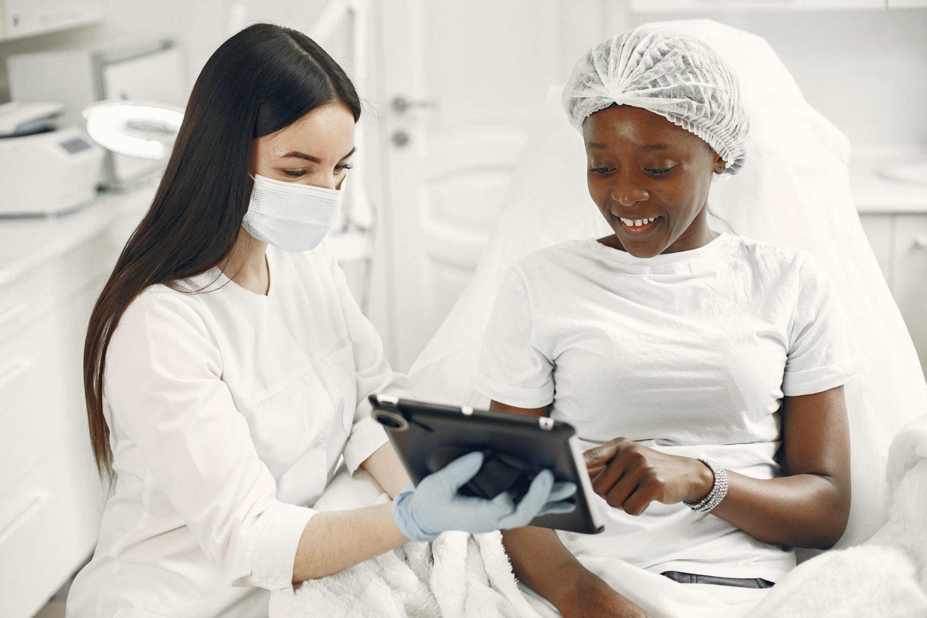 A patient and dermatologist reviewing a treatment plan on a tablet during a skincare consultation