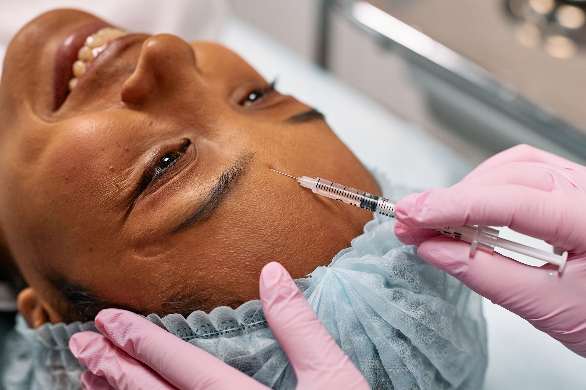 A practitioner administering an anti-wrinkle injection to a patient's forehead in a clinic